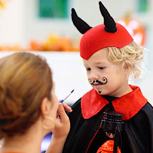 Kvinde laver halloween ansigtsmaling på dreng i djævlekostume