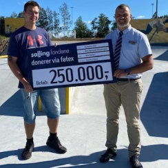 lokal donation Randers ildsjeald og varehuschef med skilt i solskin