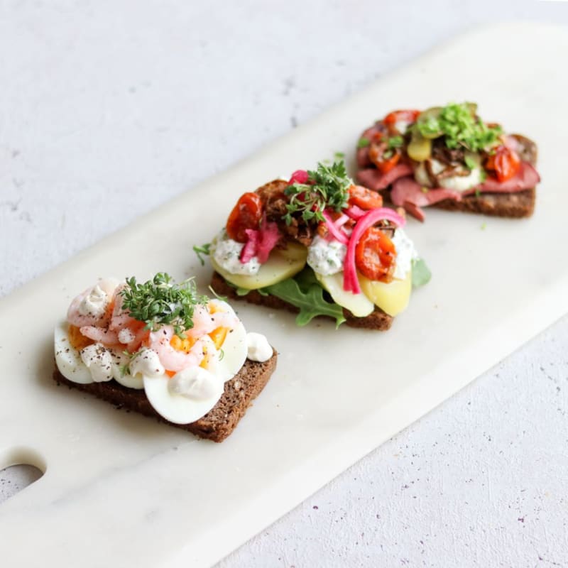 Højtbelagt smørrebrød i form af æggemad, kartoffelmad og roastbeef