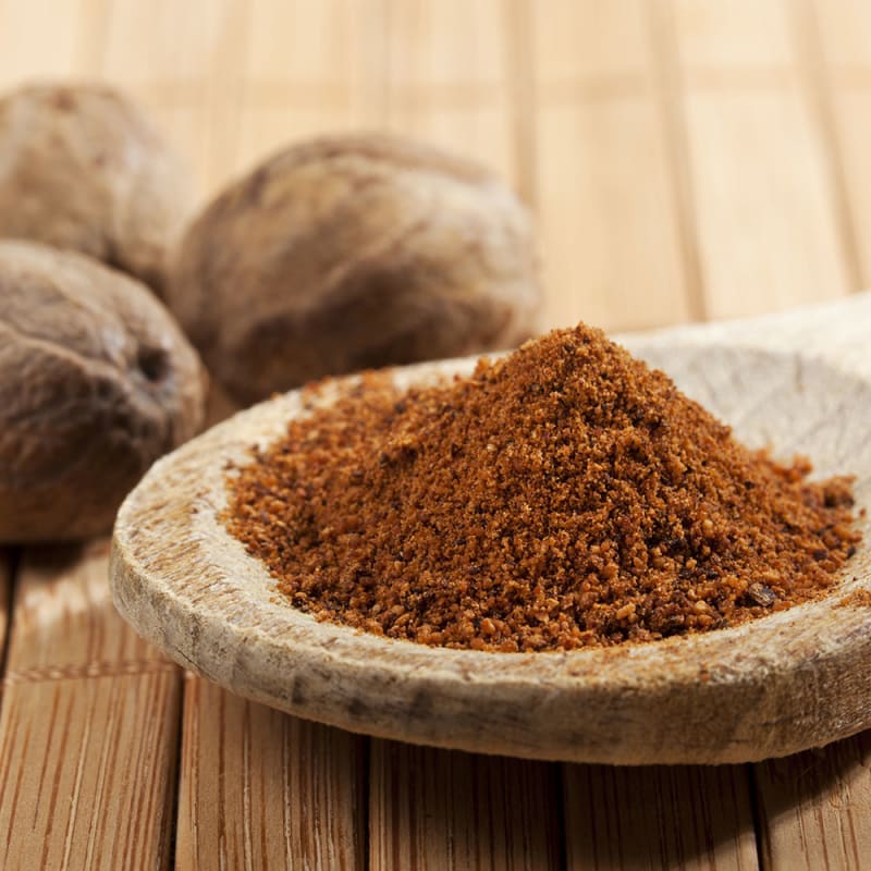 muuskatnød hele og stødt muskatnød i træske på træbord