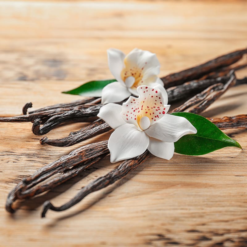 Vaniljestænger og blomster på bord