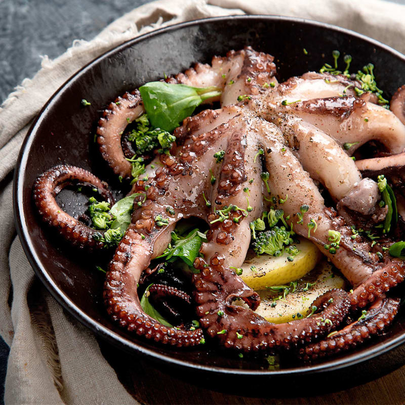 Grillet hel blæksprutte på tallerken med grønt