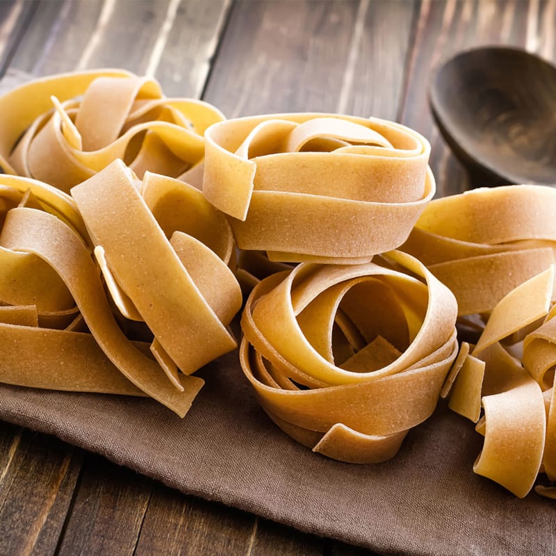 Tørret pappardelle pasta på skærebræt