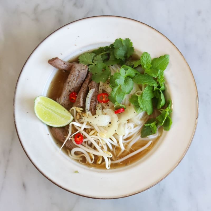 Pho suppe med oksekød, nudler, urter, chili og lime
