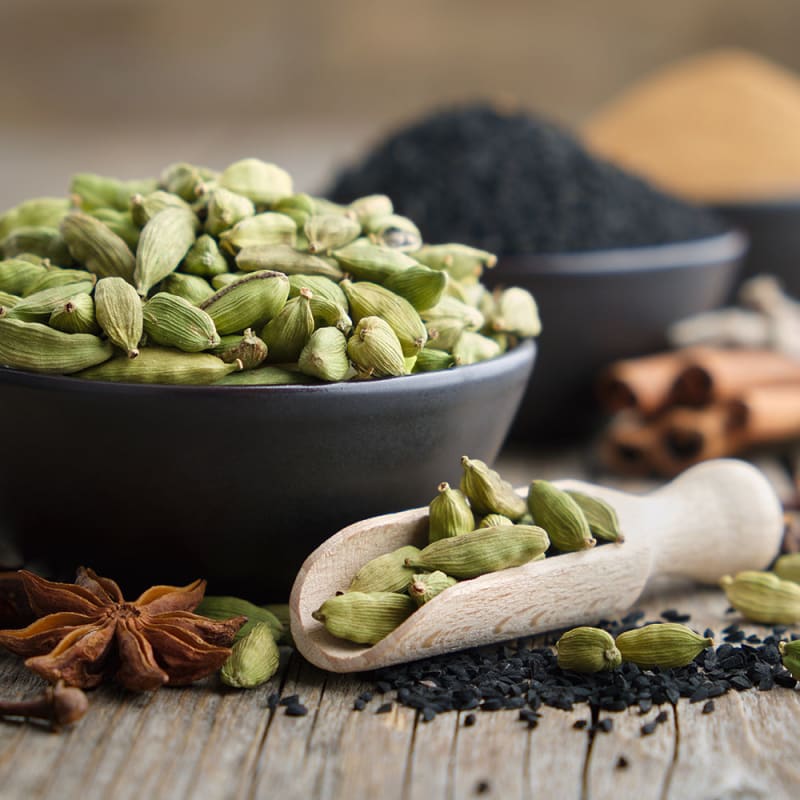 kardemomme i skål og på træske sammen med andre krydderier