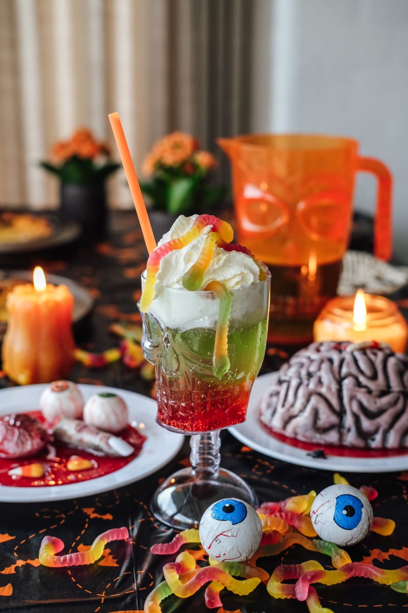 Grøn halloweendrink med flødeskum og vingummiorme