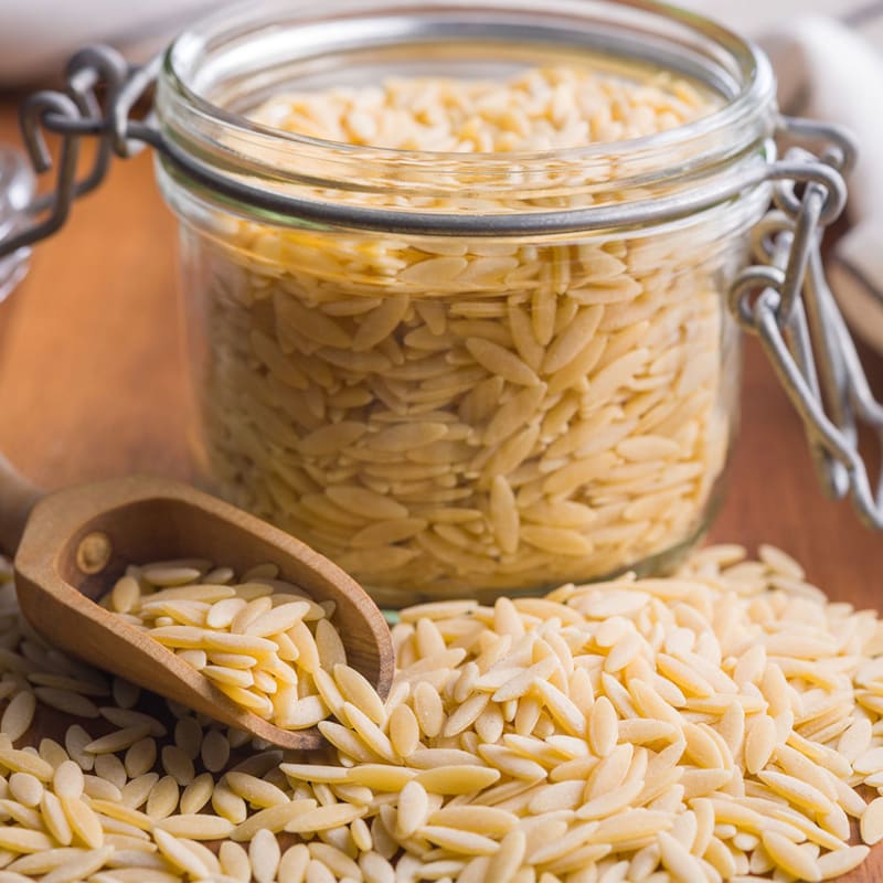 Rå orzo pastaris på bord og i beholder