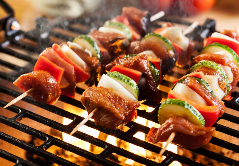 Grillspyd med grøntsager og kød på grill med direkte varme